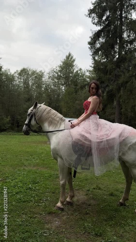 Model in a pink gown changing poses on a white horse