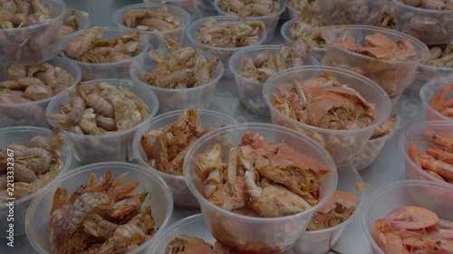 Multiple clear plastic containers hold assorted cooked crustacean seafood, neatly arranged on a flat table surface.