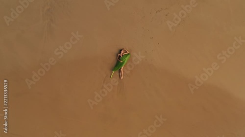 Woman Lying on Sandy Beach Under a Large Banana Leaf Top View
