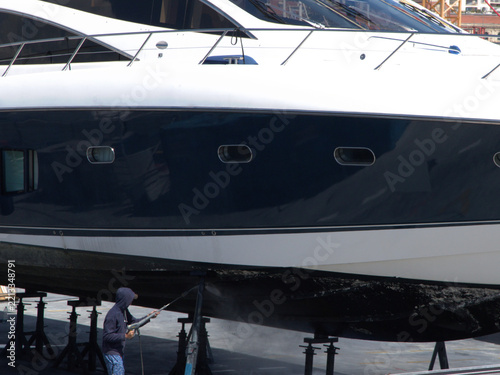 Worker Pressure Washing the Hull of a Luxury Yacht in Dry Dock