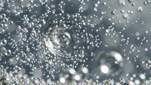 Air bubbles spinning in a vortex inside a clear liquid medium seen in close
