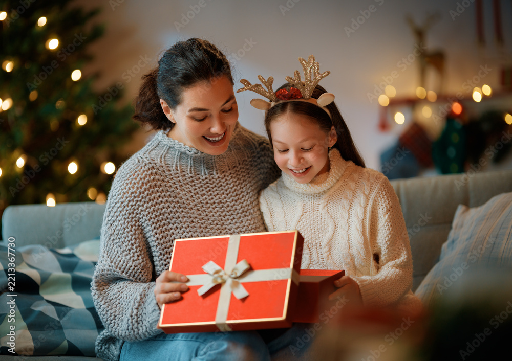 Fototapeta premium Mother and Daughter Opening Christmas Gift by Tree