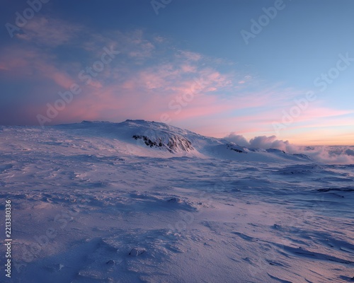 Snow-covered mountain ridge under pastel sky with soft clouds