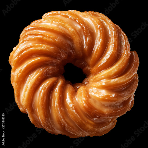 Shiny glazed cruller donut isolated on black background with clipping path, concept of sweet dessert appeal treat