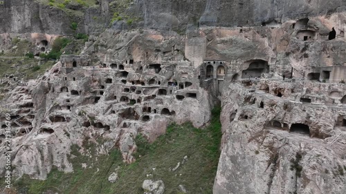 Vardzia cave monastery aerial view revealing the ancient rock hewn city and historical landmark with tourists exploring the archeological site in southern Georgia