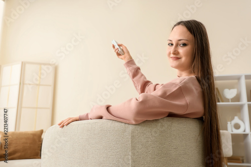 Home comfort and relaxation, young woman sitting on a cozy armchair using a r...