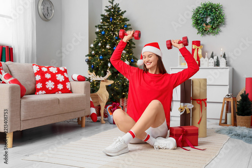 Holiday fitness and healthy lifestyle, happy woman in santa hat exercising wi...