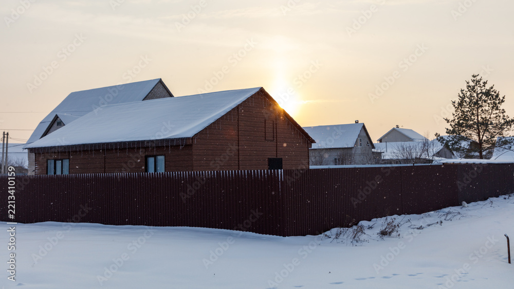 Obraz premium Snow blankets a wooden house with a tall fence
