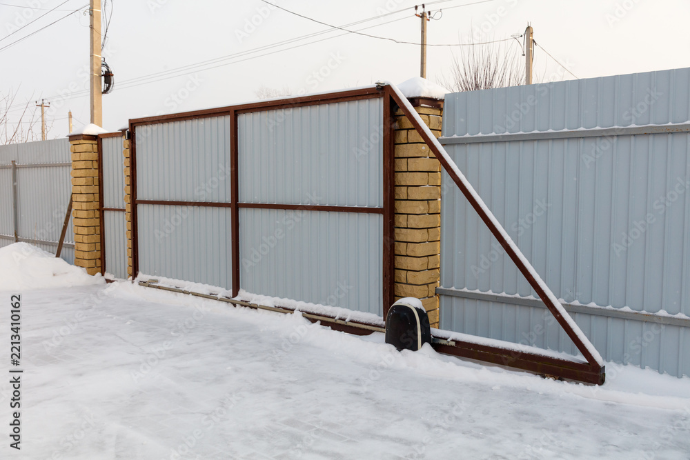 Obraz premium Snow-covered metal gate with brick pillars