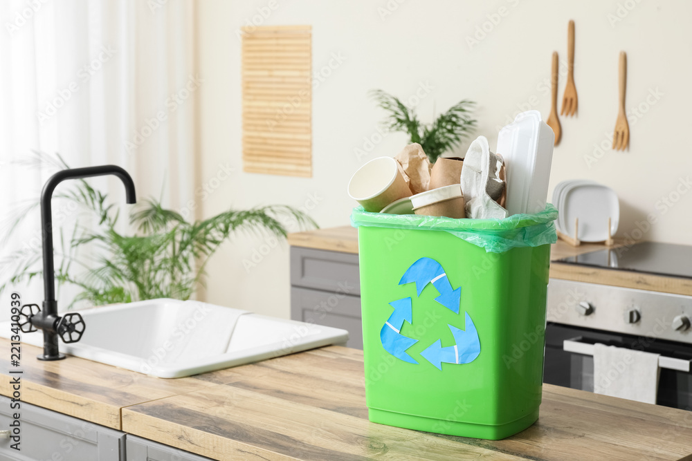 Naklejka premium Recycling and waste management, green bin with paper and plastic trash in a home kitchen for sustainable living and environmental conservation efforts