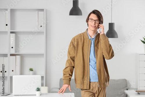 Remote work communication, young man talking on smartphone in modern office w...
