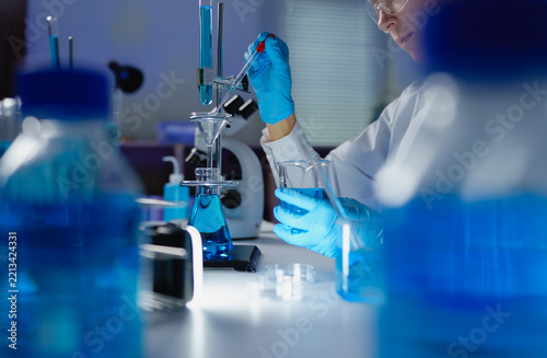 Scientist wearing gloves pipetting liquid in laboratory
