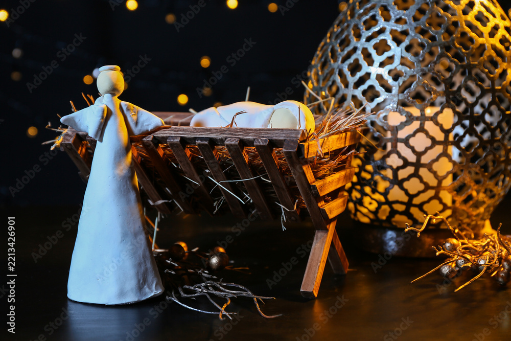 Fototapeta premium Manger with baby, angel and lantern on dark background. Christmas story concept