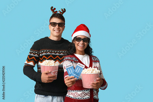 Beautiful young couple in 3D glasses with cinema tickets and buckets of popco...