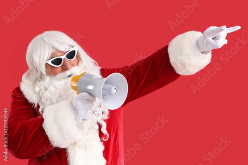 Cool Santa Claus with megaphone pointing at something on red background