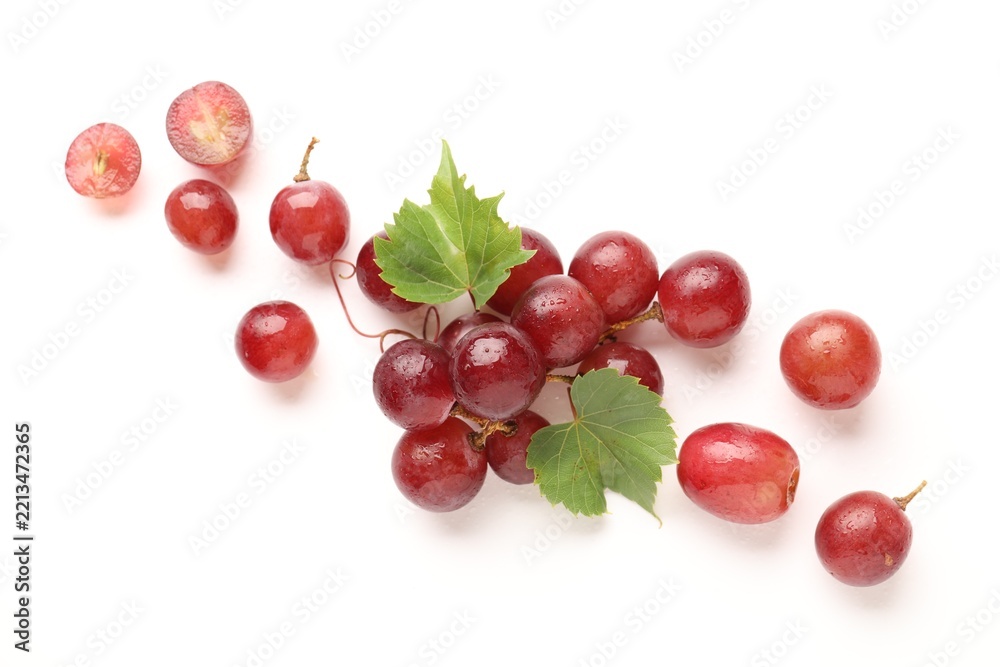 Fototapeta premium Fresh ripe grapes and green leaves on white background, flat lay