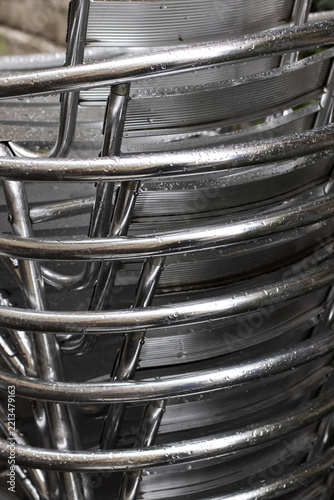 Rain Soaked Stacked Silver Metal Chairs at an Outdoor Cafe in Late Autumn. Close-up.
