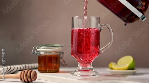 Cozy warm tea preparation with honey and lemon, pouring hot tea in glass cup from french press