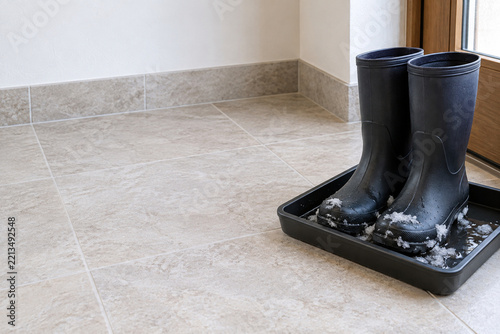 Wet winter boots draining in tray by entrance