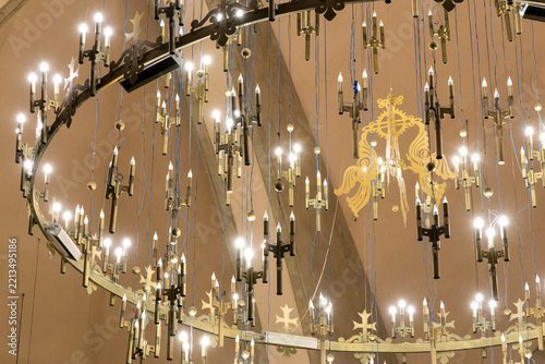 Rows of candle shaped bulbs and gilded cross ornaments hang in symmetry from the brass chandelier inside Saint Gregory the Illuminator Cathedral, Yerevan, Armenia
