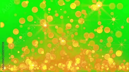 Golden yellow floating bokeh particles rising against a bright green chroma key background screen