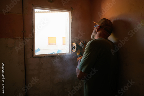 Construction worker using angle grinder remodeling window frame