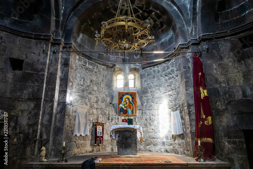 Stone altar decorated with painted icons fabric banners and a hanging chandelier stands inside the ancient monastery church in Gegharkunik Province, Artsvanist, Armenia