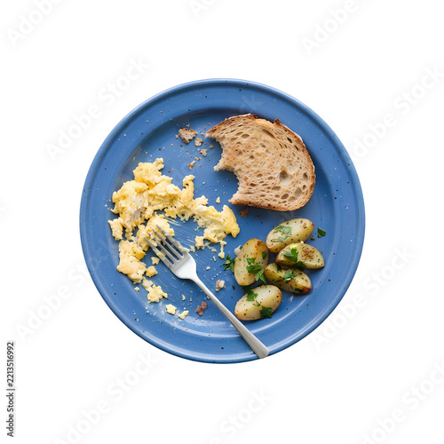 Scrambled eggs, roasted potatoes, and bitten toast leftovers on a blue plate isolated. Partially eaten breakfast meal with a silver fork png. Messy food scraps remaining after morning meal isolated.