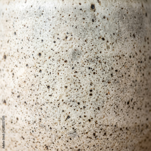Macro close-up of speckled ceramic pottery surface with iron spots