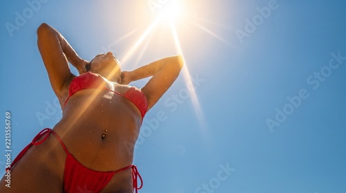 Low Angle View of Beautiful Tanned Woman in Red Bikini Taking Outdoor Shower. Summer Lifestyle Concept Banner with Copy Space