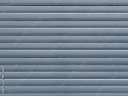 Geschlossener blauer Rollladen mit horizontalen Lamellen und feiner Rillenstruktur als Hintergrund mit Textfreiraum