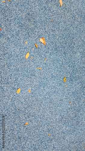 Urethane flooring texture, sports field flooring, playground flooring, texture with mixed blue and white granules, yellow autumn fallen leaves, background, wallpaper