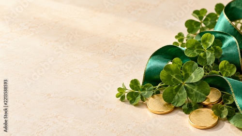 Green shamrocks with emerald ribbon and gold coins on ivory stone