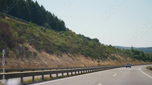 Highway traffic through forested hills a white pickup truck and a truck ahead