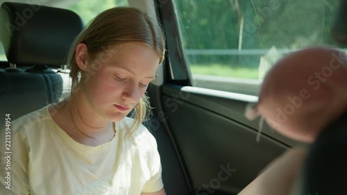 A tired and upset girl in the back seat of a car slow motion a red face from the heat