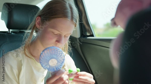 A girl with a toy and a handheld fan in the car slow motion