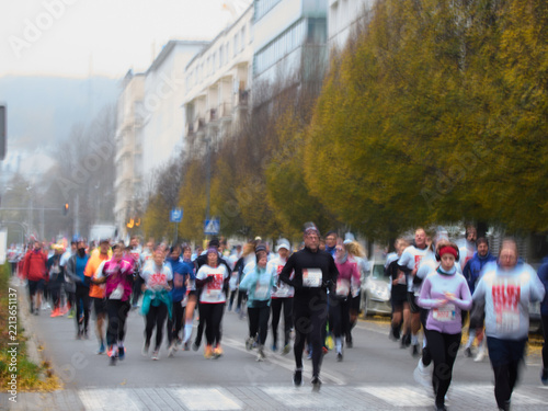 Runners participating in an autumn city marathon. Dynamic shot with intentional motion blur effect, showcasing the speed and energy of the street race participants.