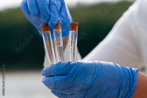 scientist gloved hands holding water sample test tubes microplastic pollution testing river lake environmental research concept of ecology contamination science