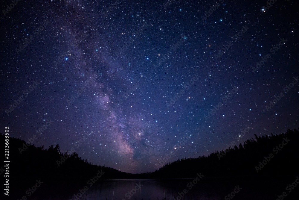 Fototapeta premium Milky Way Reflected Over Calm Lake and Forest at Night