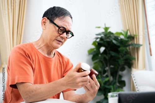 Elderly man examining prescription pill bottle labels