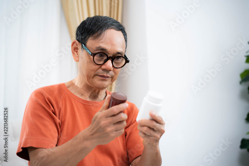 Elderly man examining prescription pill bottle labels