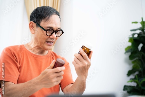 Elderly man examining prescription pill bottle labels
