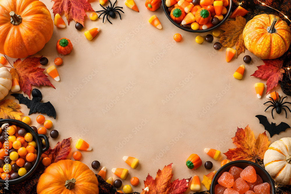 Fototapeta premium Halloween candy border surrounding clean central copy space, featuring colorful sweets, pumpkins, autumn leaves, spiders, and festive seasonal decoration.