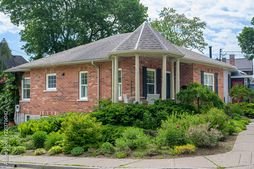 Fotografie Single-story brick house with wraparound porch and landscaped corner garden