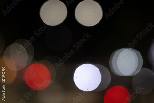 Obraz na plátně Abstract out of focus night bokeh lights with bright white and red circular orbs on dark background
