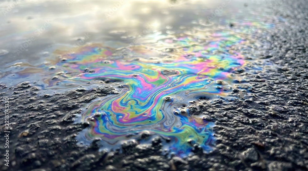 Fototapeta premium Iridescent Oil Slick on Asphalt Reflecting Sky Colors