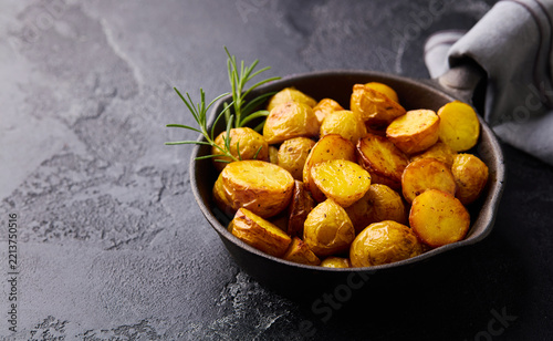 Roasted baby potatoes in iron skillet. Dark grey background. Copy space. Close up.