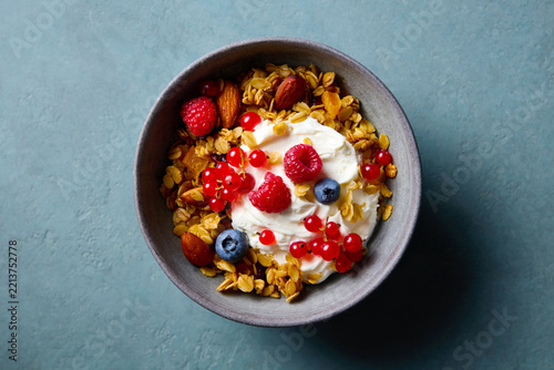 Healthy breakfast. Granola, muesli with yogurt and fresh berries. Blue grey background. Close up. Top view.