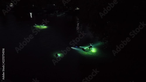 An aerial view shows snorkelers exploring a shallow underwater habitat at night in Lembeh Strait, Indonesia. This area of North Sulawesi is famous for its rare, black sand-associated marine life.