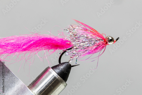 Bright silver and pink streamer fly on a tying vice ready to take fishing for steelhead
